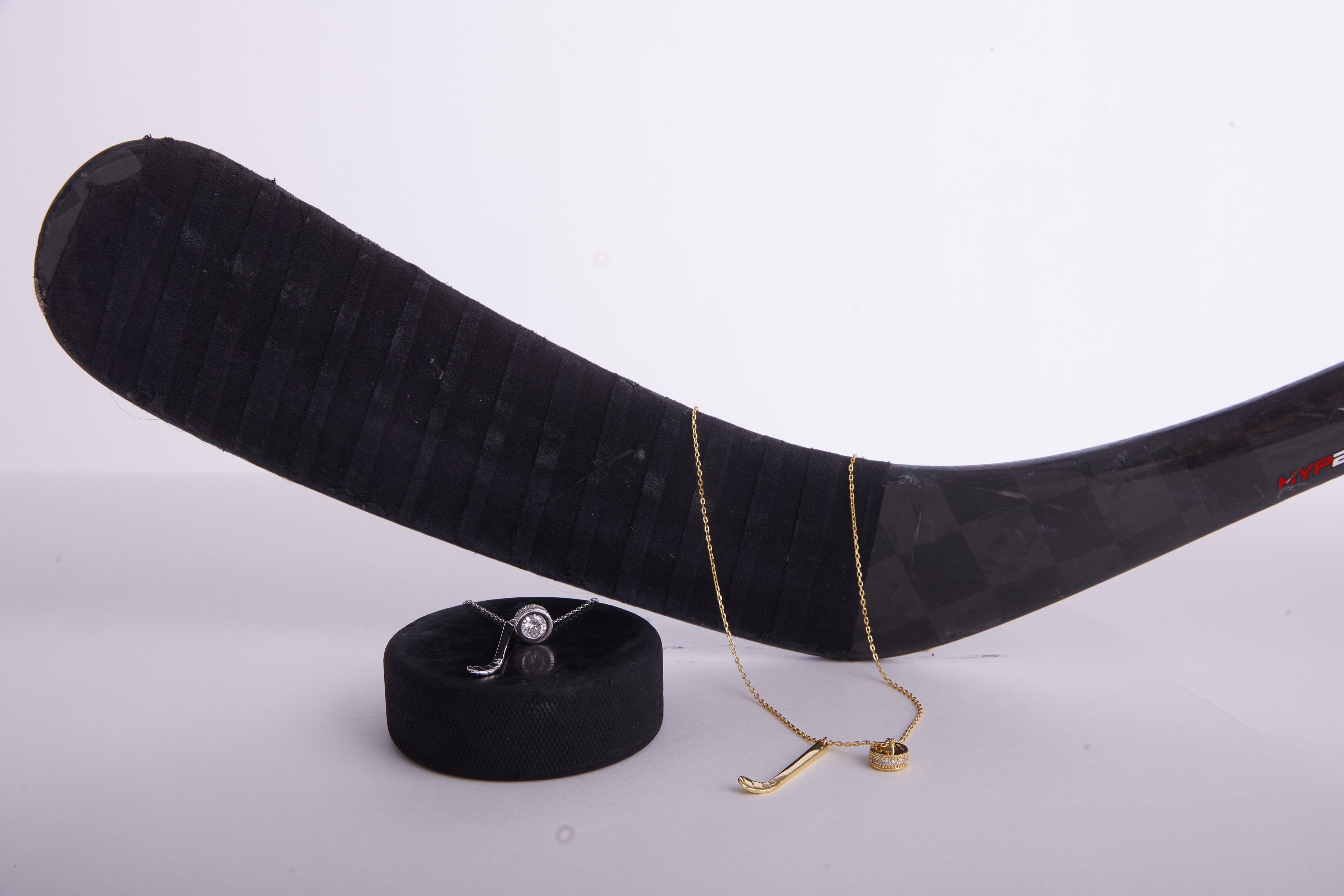 Hockey stick with a gold necklace and ring on a white background