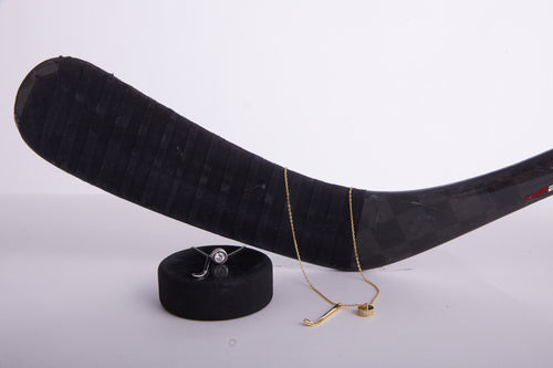 Hockey stick with a gold necklace and ring on a white background